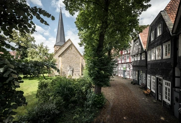 Kirchplatz Apostelkirche © Detlef Güthenke.jpg Kirchplatz mit Apostelkirche, spitzem Turm, Fachwerkhäusern und Bäumen in Gütersloh
