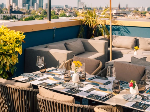 The Blasky Rooftop Leerer Lounge- und Essbereich auf einer sonnigen Dachterrasse.