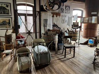 Historische Mühle mit Maschinen und Alltagsgegenständen ausgestellt auf einem hölzernen Boden.