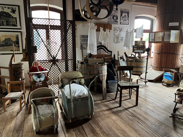 Historische Mühle mit Maschinen und Alltagsgegenständen ausgestellt auf einem hölzernen Boden.