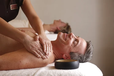Ein Mann mittleren Alters genießt eine entspannende Rückenmassage in einem Wellness-Bereich.