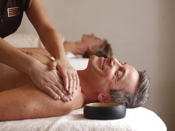 Ein Mann mittleren Alters genießt eine entspannende Rückenmassage in einem Wellness-Bereich.