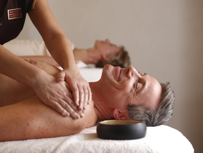 Ein Mann mittleren Alters genießt eine entspannende Rückenmassage in einem Wellness-Bereich.