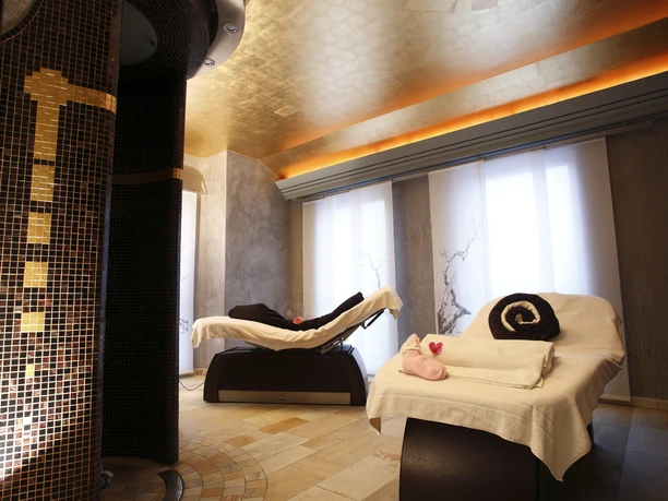 Zwei Massagebänke in einem stilvollen Spa mit warmen Licht, dekorativen Kacheln und entspannender Atmosphäre.