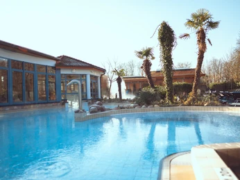 Außenbereich eines Freizeitbades mit Palmen und übriger Vegetation, die eine tropische Atmosphäre schafft.