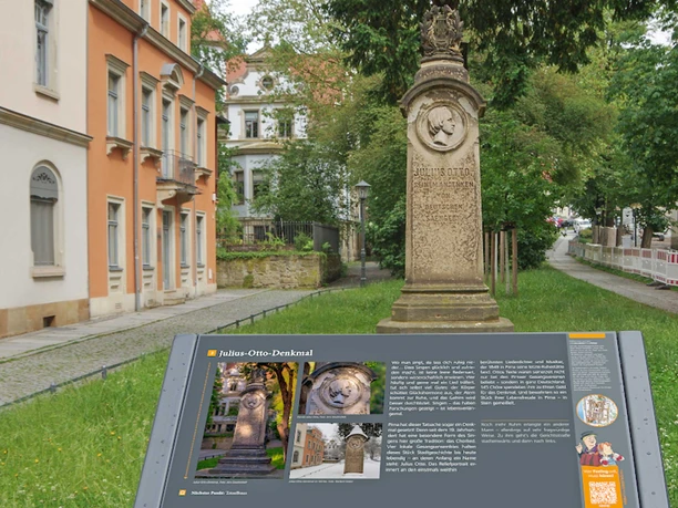 Stenen Julius Otto monument met reliëf in een groen park, met een informatiebord ernaast. Op de achtergrond zijn historische gebouwen te zien.