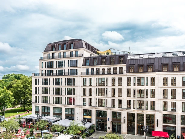 Sofitel Frankfurt Opera Großes modernes Gebäude am Opernplatz mit Cafés und Bäumen davor.