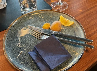 Aufgegessen, war lecker!-Platzhalterbild.jpg Leerer Teller mit Messer, Gabel, zwei Kartoffeln und Zitronenscheibe, daneben ein Wasserglas.