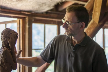 4.21_Bildhauer Thorsten Held_LandArt-Station 4.21.jpg Der Bildhauer Thorsten Held arbeitet konzentriert an einer Tonfigur in einem lichtdurchfluteten Atelier.
