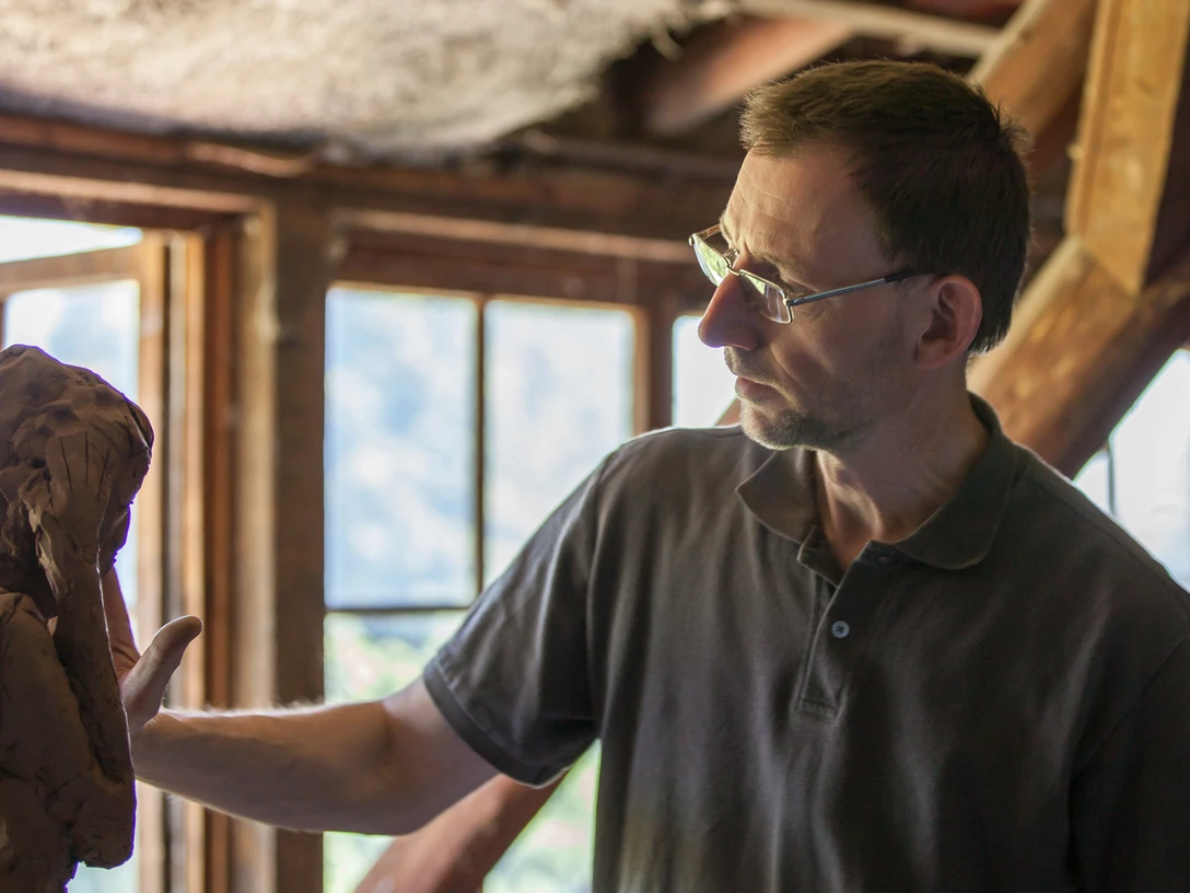 4.21_Bildhauer Thorsten Held_LandArt-Station 4.21.jpg Der Bildhauer Thorsten Held arbeitet konzentriert an einer Tonfigur in einem lichtdurchfluteten Atelier.