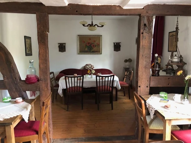 Ruhiger Raum mit Holzbalken, antiken Möbeln und Sitzgruppe, ideal für entspannte Gespräche.