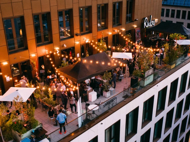 Evening rooftop bar scene with string lights and guests