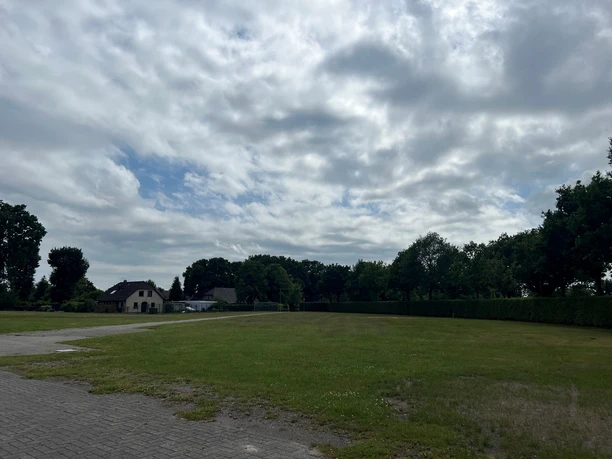 Wohnmobilstellplatz Schützenplatz1.jpg Der Stellplatz liegt unter bewölktem Himmel, von Bäumen umrahmt, mit einem großen Rasenfeld.