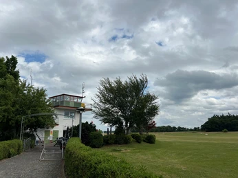 Bild2.jpg Tower für die Flugzeuge am Rande der Flugbahn zwischen Bäume. Davor ist ein Fahrradständer zu sehen.