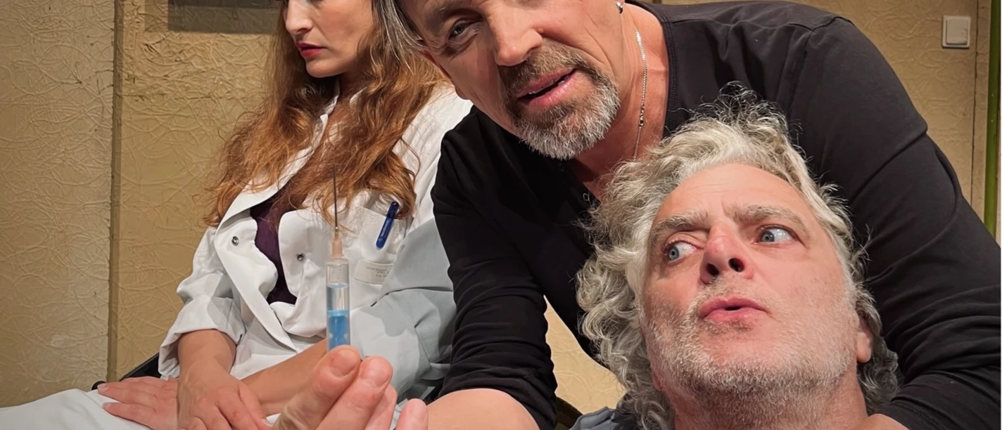 5MB©BKT.png Ein Mann zeigt einer nachdenklichen Frau einen Gegenstand, während ein anderer Mann besorgt schaut.