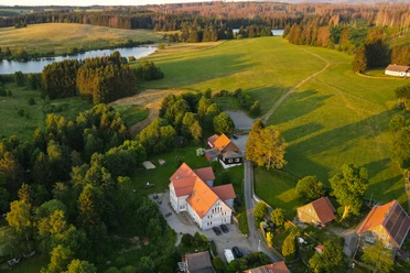 Harz-Urlaubs-Alm in Buntenbock - Hotel, Wiesen und Teich aus der Luft Die Luftaufnahme zeigt das idyllisch gelegene Hotel Urlaubs-Alm Buntenbock im Harz, umgeben von saftigem Grün und einem Teich. Ein perfekter Rückzugsort inmitten der Natur.