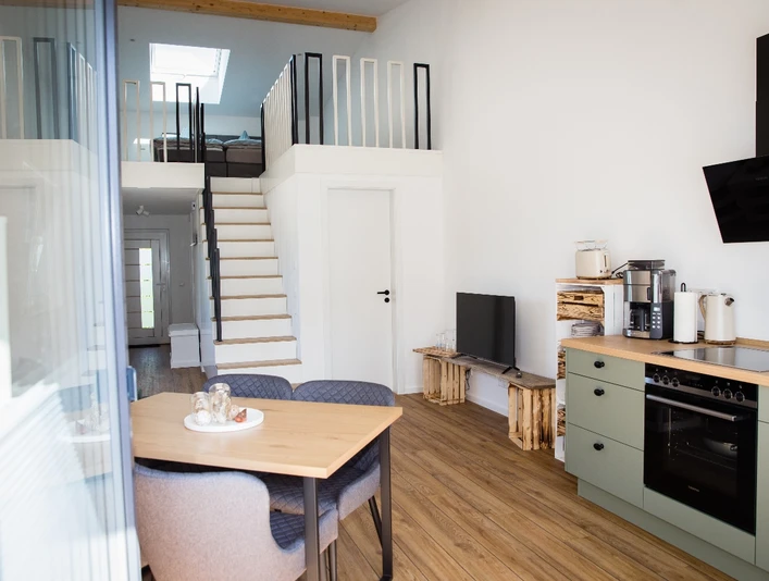 Bröcklingshof_Fewo (15).jpg Helle Ferienwohnung mit offenem Wohnbereich, moderner Küche, Esstisch und einer Treppe zur Galerie.