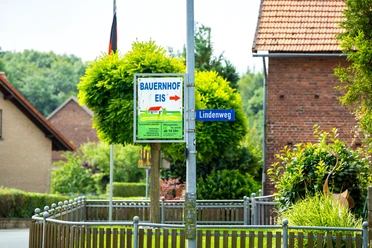 Foto-208.jpg Ein Wegweiser mit der Aufschrift "Bauernhof Eis" führt zum Lindenweg in einem ländlichen Dorf.