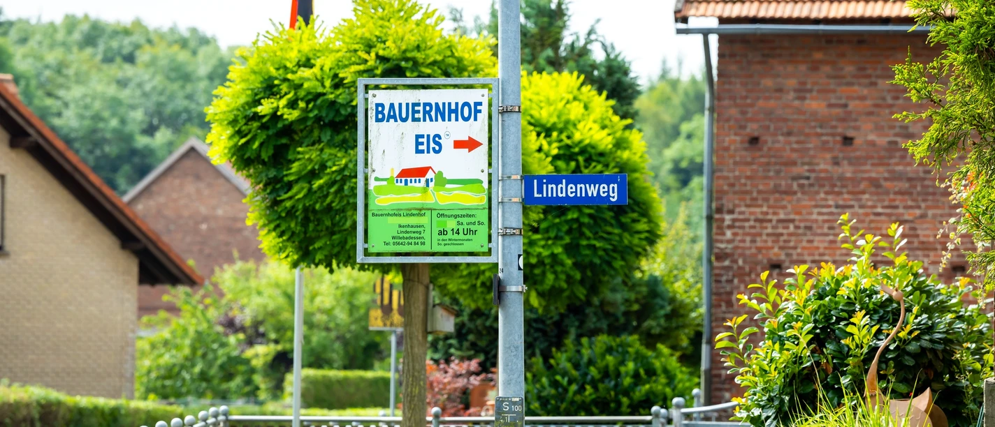 Foto-208.jpg Ein Wegweiser mit der Aufschrift "Bauernhof Eis" führt zum Lindenweg in einem ländlichen Dorf.