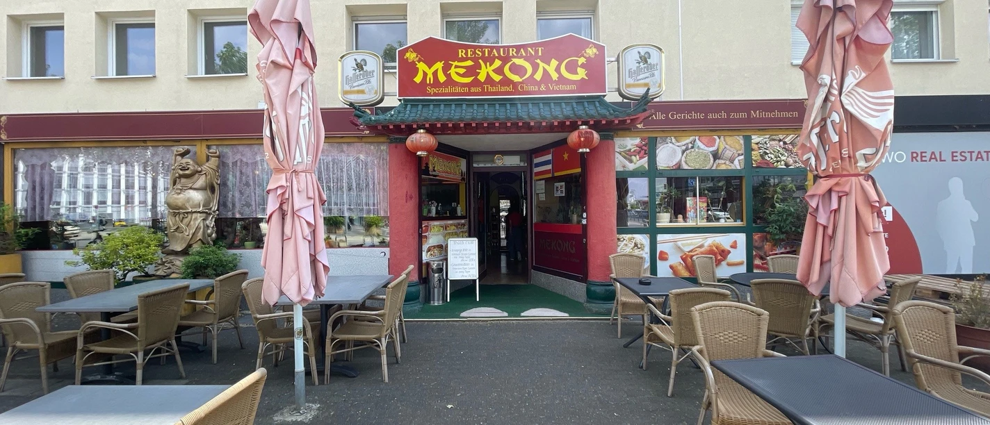 Mekong.jpg Man sieht den Eingang des Restaurants Mekong sowie leere Tische und Stühle vor dem Eingangsbereich.