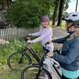 Radfahren in der Mittelweser-Region Zwei Frauen mit Fahrradhelmen pausieren auf E-Bikes neben einem Feldweg, angrenzend an Bäume.