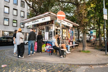 King Georg Kiosk Small kiosk in an urban setting, surrounded by trees and people in a relaxed atmosphere.