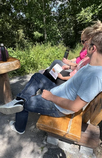 Radfahren in der Mittelweser-Region Ein Paar sitzt auf einer Holzbank in einem schattigen Park, neben ihnen stehen Fahrräder.
