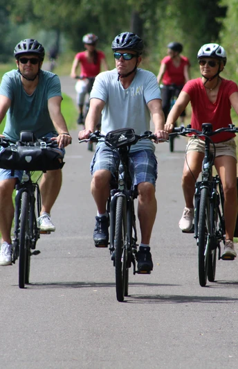 Radfahren in der Mittelweser-Region Eine Gruppe Radfahrer mit Helmen unterwegs auf einem asphaltierten Weg durch grüne Landschaft.