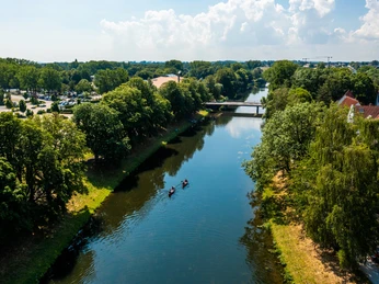 herford-kanu-teutoburger-wald-tourismus-h-tornow-012-jpg.jpg Zwei Kanus gleiten einen von Bäumen gesäumten Fluss in Herford entlang, unter einer Brücke hindurch.