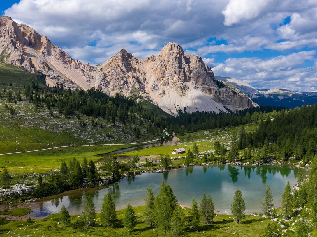 Dolomiten_Kal. SHS.jpg Ein malerischer Bergsee, umgeben von saftig grünen Wiesen und majestätischen Dolomiten, unter strahlend blauem Himmel.