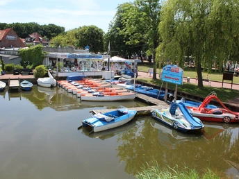 Steinhuder Meer Bootsverleih am Steinhuder Meer mit Tretbooten unterschiedlicher Formen und Farben, umgeben von Grünen.