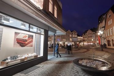Weinrichs Bruchbude Gänsemarkt Herford-Ludwig Weinrich GmbH & Co KG.jpg Leuchtende Fassaden und Fußgänger auf dem Gänsemarkt in Herford bei abendlicher Beleuchtung.