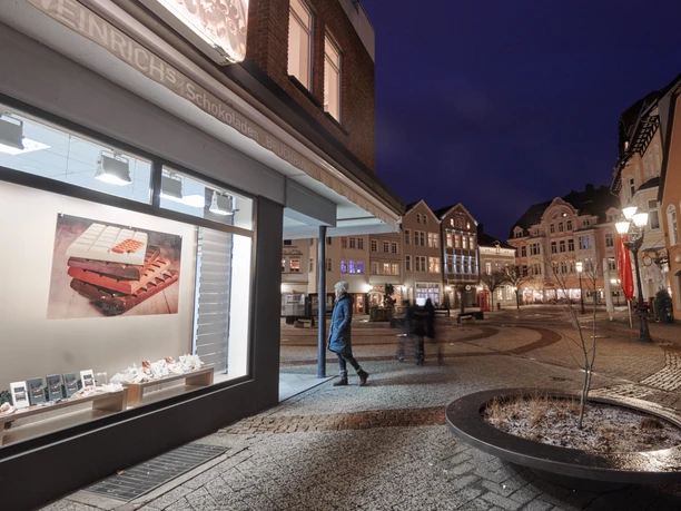 Weinrichs Bruchbude Gänsemarkt Herford-Ludwig Weinrich GmbH & Co KG.jpg Leuchtende Fassaden und Fußgänger auf dem Gänsemarkt in Herford bei abendlicher Beleuchtung.