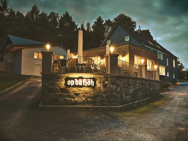 Restaurant Op dä Höh in Hattingen Einladendes Restaurant mit Terrasse und gemütlichen Lichtern in grüner Umgebung am Abend.