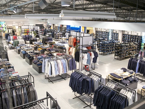 Innenraum Ahlers Fashion Outlet Herford- WTW Adolf Ahlers Stiftung & Co KG Herford.jpg Großzügiger Verkaufsraum mit modern präsentierter Herrenbekleidung auf Kleiderständern und Regalen.
