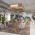 Ein modernes Modegeschäft mit einer komfortablen Lounge, umgeben von Pflanzen und eleganter Dekoration.