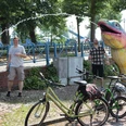 Radfahren in der Mittelweser-Region Menschen genießen einen sonnigen Tag in einem Park, umgeben von Fahrrädern und einer großen, bunten Skulptur.