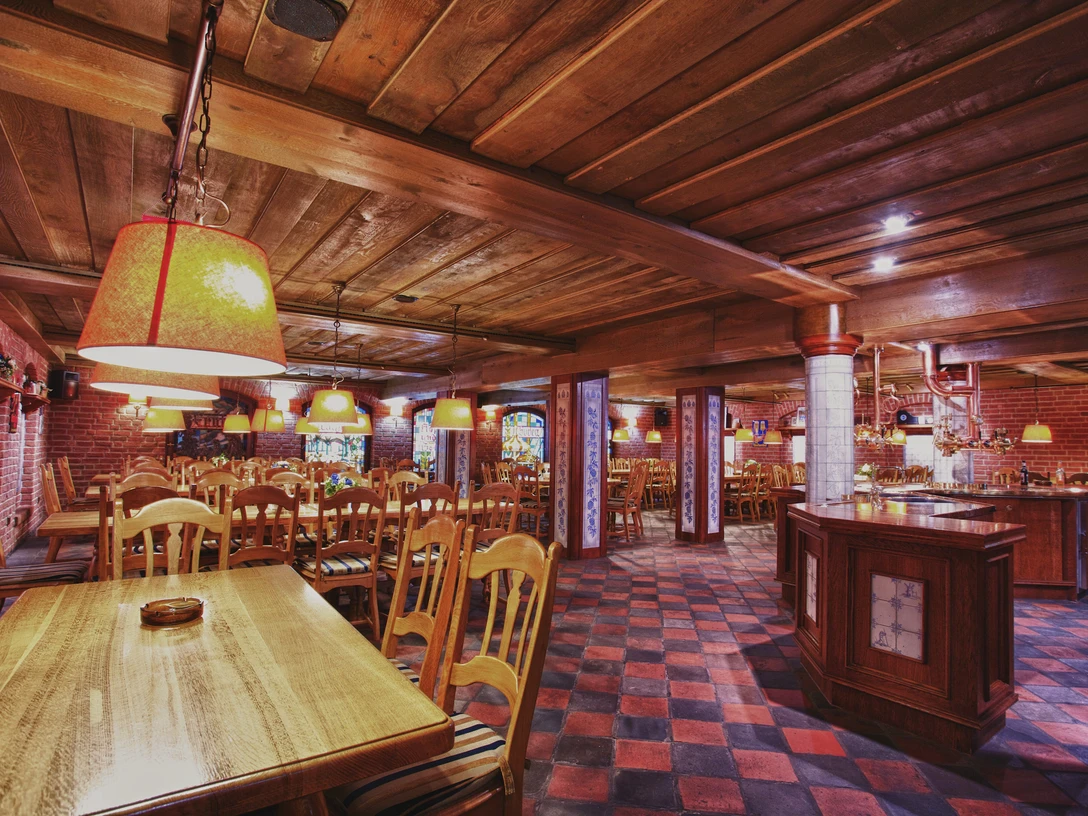 Ein rustikaler Raum mit Holztischen, Stühlen und warmen Beleuchtung für gesellige Brauereirunden.