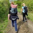 Wandern in der Mittelweser-Region Zwei Frauen wandern auf einem schmalen Waldweg in sommerlichen Outfits und tragen Rucksäcke.