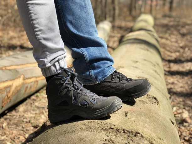 Two pairs of hiking boots on a fallen tree trunk in the wooded area of the Mittelweser region.