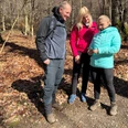 Wandern in der Mittelweser-Region Drei Personen stehen auf einem Waldweg in herbstlichem Laub, betrachten interessiert ein Smartphone.