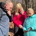Group hiking in a sparse deciduous forest, focused on a smartphone as a hiking aid in the autumnal surroundings.