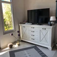 Ein freundlich wirkendes Wohnzimmer mit einer hellen Kommode und einem großen Flachbildfernseher.