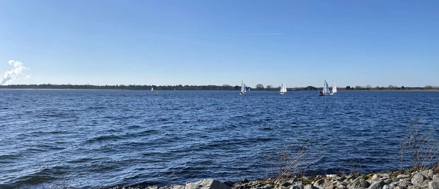 Speichersee Geeste - Winterspaziergang ©Emsland Tourismus GmbH (5) (3).jpeg Klares Winterlicht über dem Speichersee Geeste mit kleinen Segelbooten und steinigem Ufer.