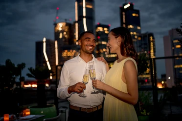 Sofitel Frankfurt Opera - Gäste Paar mit Sektgläsern auf Rooftop mit Skyline bei Nacht