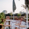 THE FLAG West M. - Dachterrasse Begrünte Rooftop-Terrasse mit leeren Stühlen bei Tageslicht