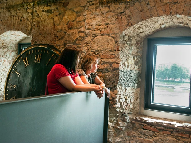 Two visitors look out the Rententurm window beside historic tower clock