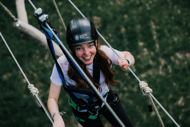 Climbing forest Junge Frau im Klettergurt lächelt beim Aufstieg im Parcours