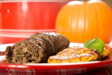 k-blankenhain-roulade-mit-kuerbisklitscher-c-andreas-krone.jpg Rinderroulade mit Kürbisklitscher auf rotem Teller, im Hintergrund ein Kürbis.