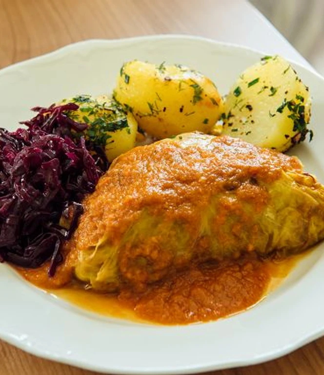 k-blankenhain-rouladen-machen-12-c-tmgs-czech-vibes.jpg Kohlroulade mit Tomatensauce, Rotkraut und Petersilienkartoffeln auf weißem Teller.